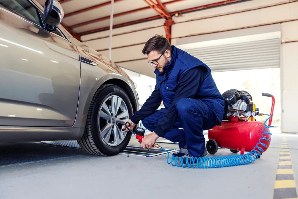 car-mechanic-service-station-tries-inflate-tires-car-with-help-compressor-man-blue-work-suit-crouched-car-workshop-works-around-car-tires by mastermechanics